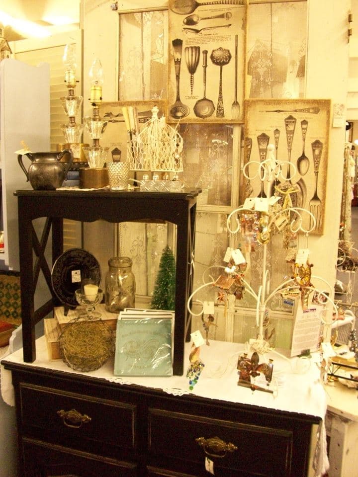 Dark dresser display with vintage silverware art prints, a crystal lamp, and a white jewelry tree of tagged items