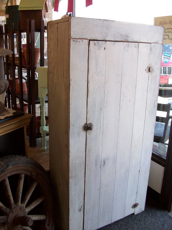 Rustic whitewashed wooden cabinet near the entrance with an antique wagon wheel and country-style pieces