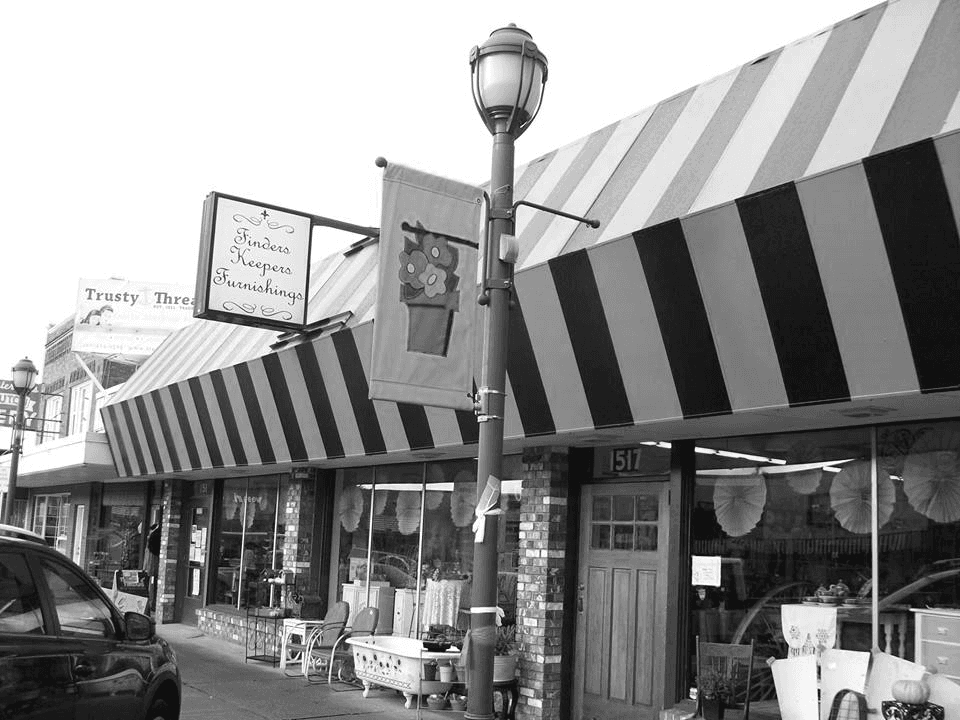 Black-and-white photo of the Finders Keepers storefront at 1517 3rd Street under its bold striped awning and hanging sign